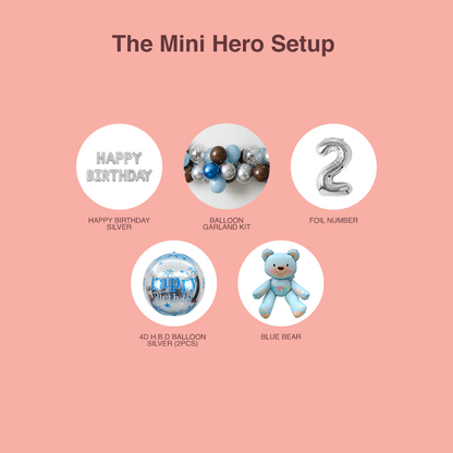 Miniature birthday setup items including 'Happy Birthday' silver balloons, balloon garland kit, foil number '2', 4D HBD balloon set, and blue bear on a pink background.